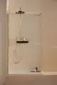 Duschsystem von Ideal Standard mit einer Wandmontage, einem Brausethermostat und einem handgeführten Duschgriff. Transparentes Trennwand-Design.